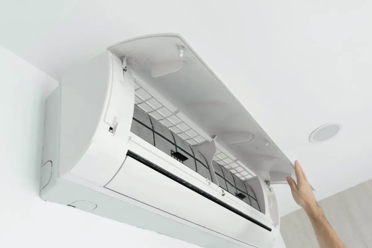 Hand opening the cover of a wall-mounted ductless air conditioner